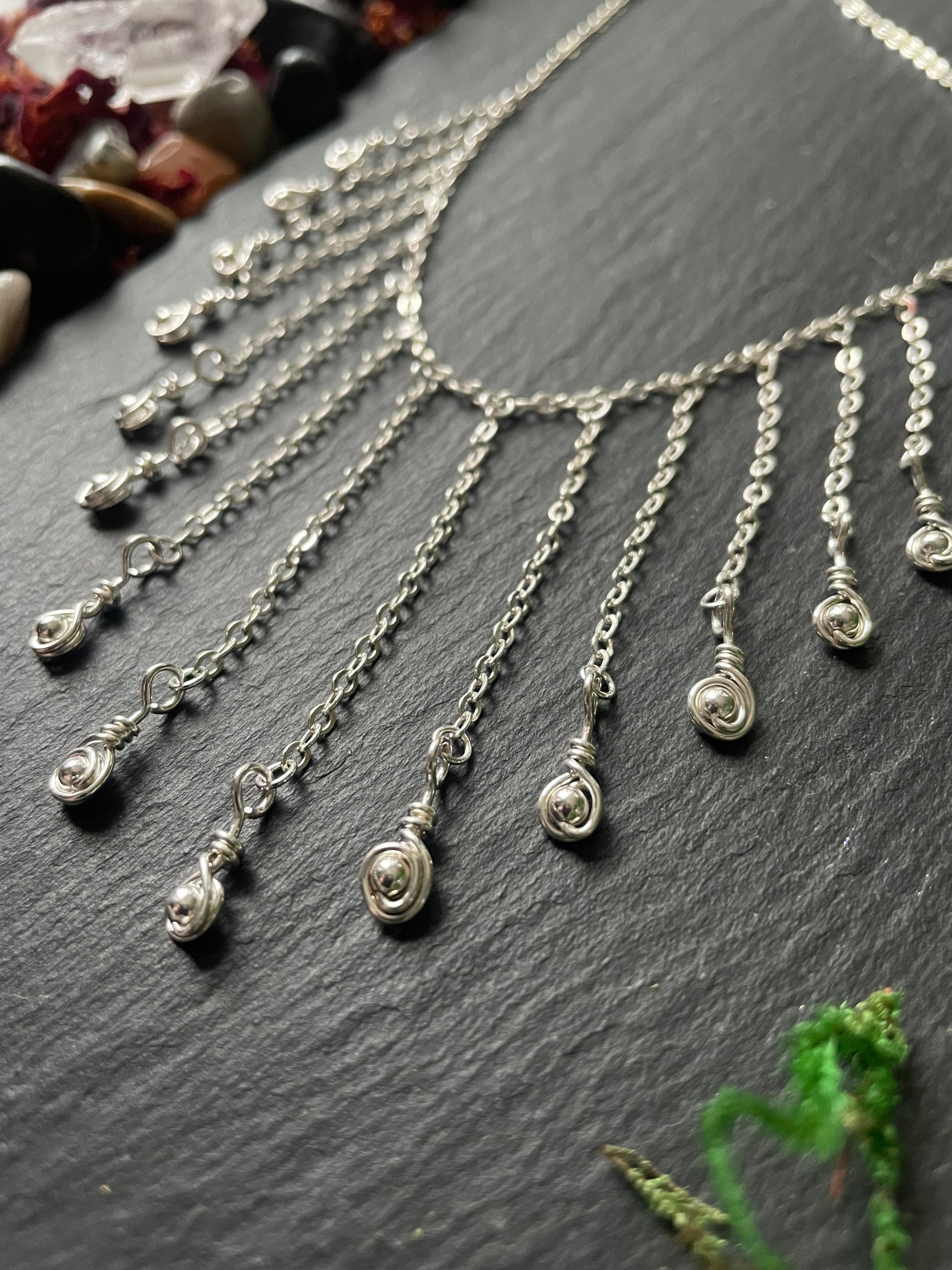 Silver necklace with teardrop charms on a dark surface