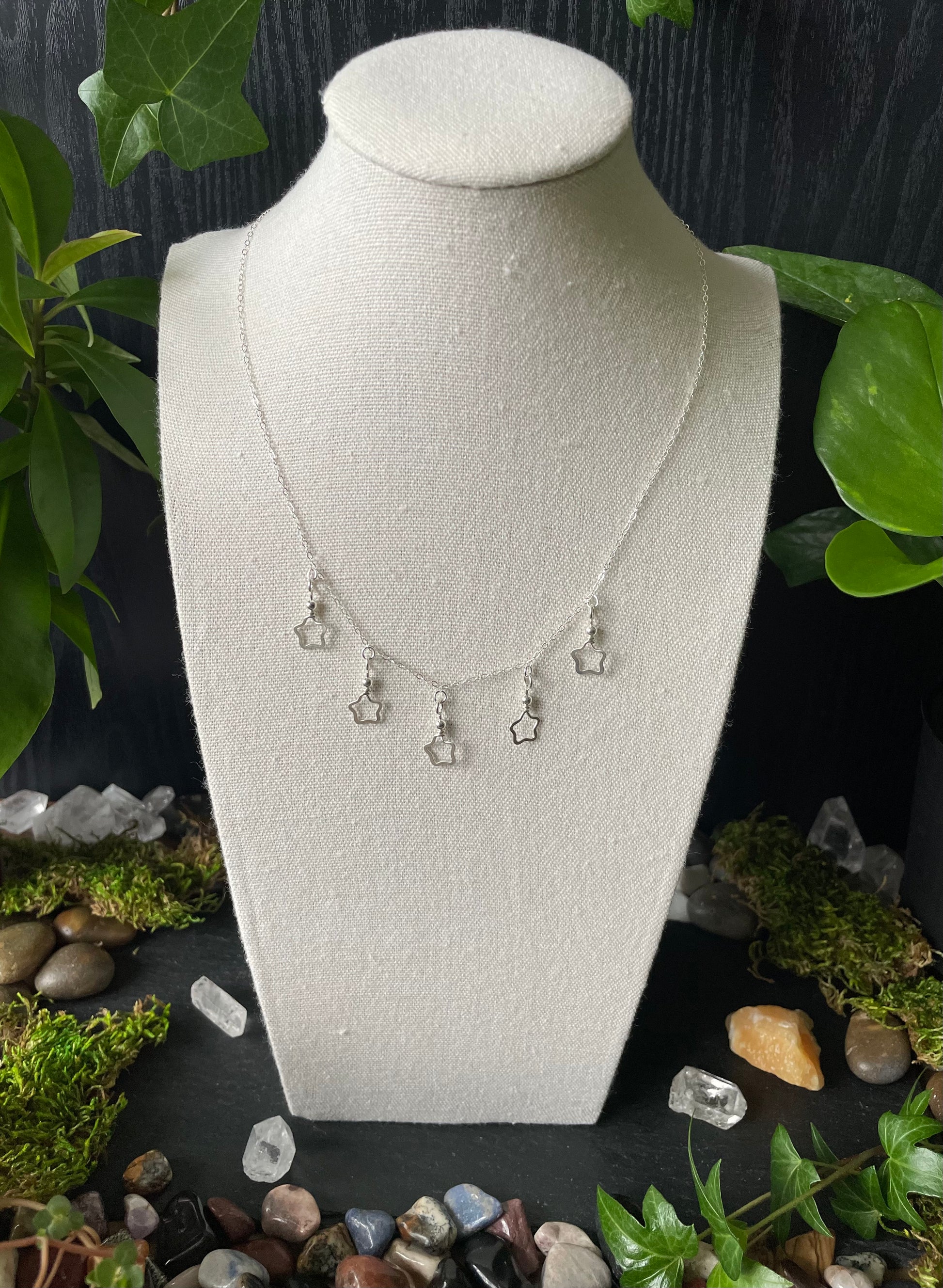 Necklace on a white bust with a natural stone and leaf background