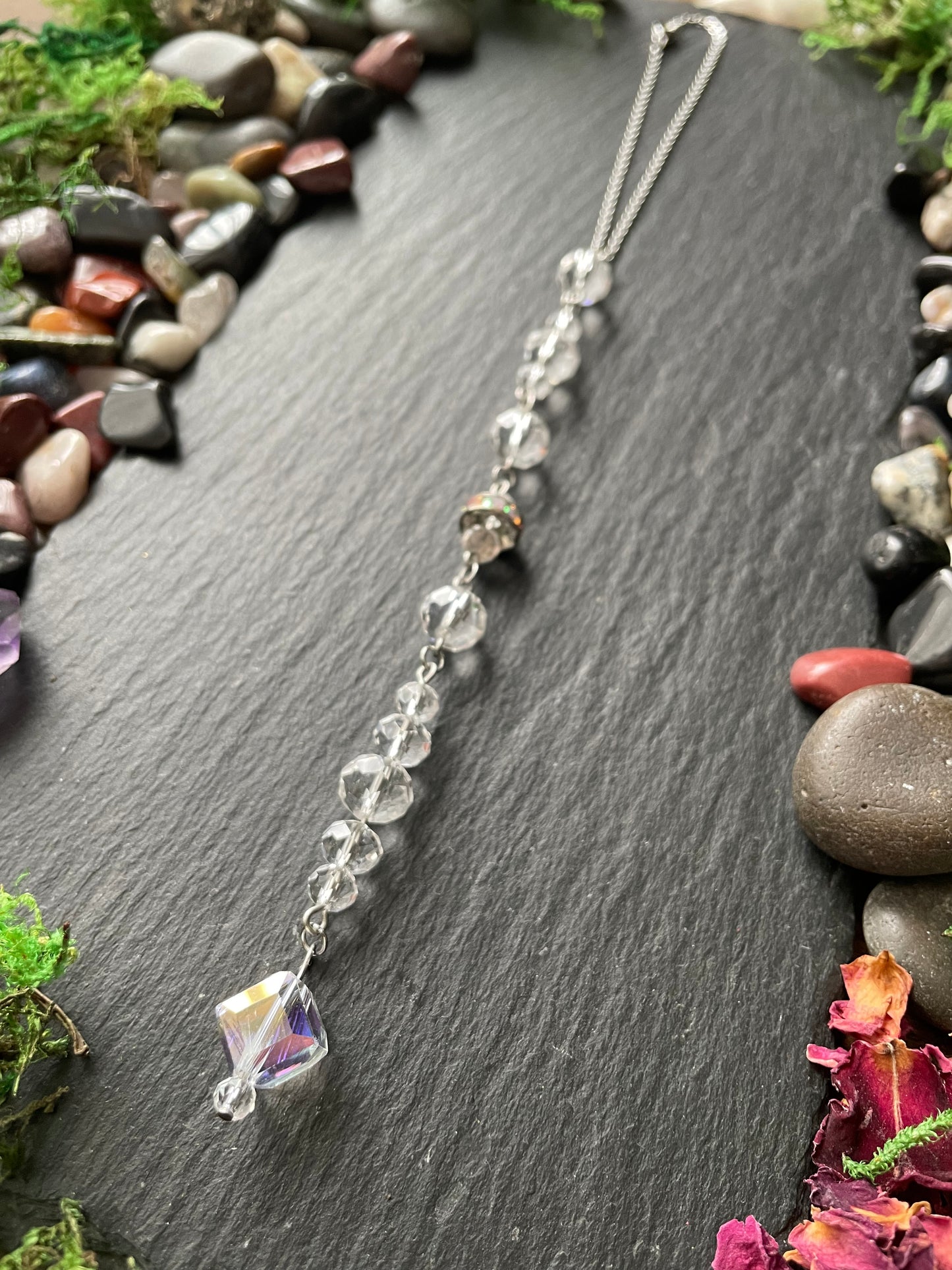 Sparkly car mirror charm on a dark stone surface with stones and moss