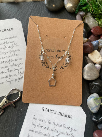 Necklace with star charm on a brown card with text, surrounded by stones and leaves.