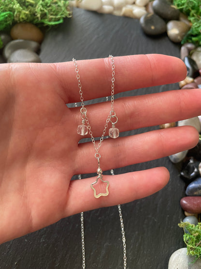 Star necklace held in a hand with a natural stone background