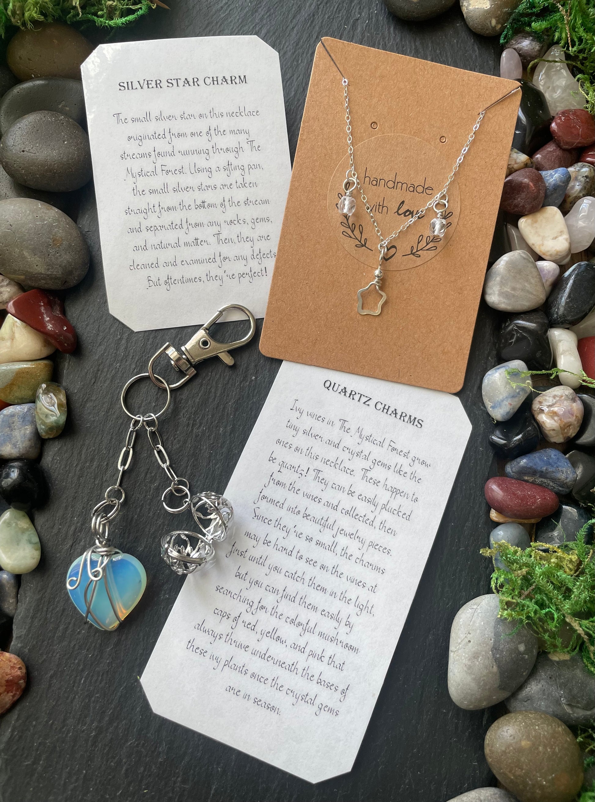Silver star charm necklace and keychain on a card with text, surrounded by stones and greenery.