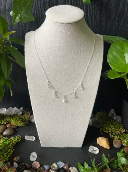 Quartz bead necklace on bust with greenery and stones in the background