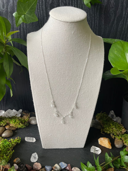 Silver quartz bead necklace on white bust a black surface with greenery and stones