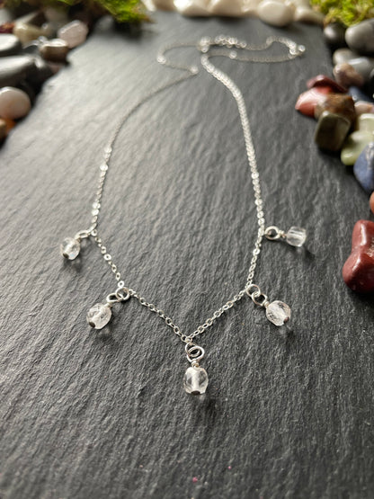 Silver necklace with clear beads on a dark stone surface