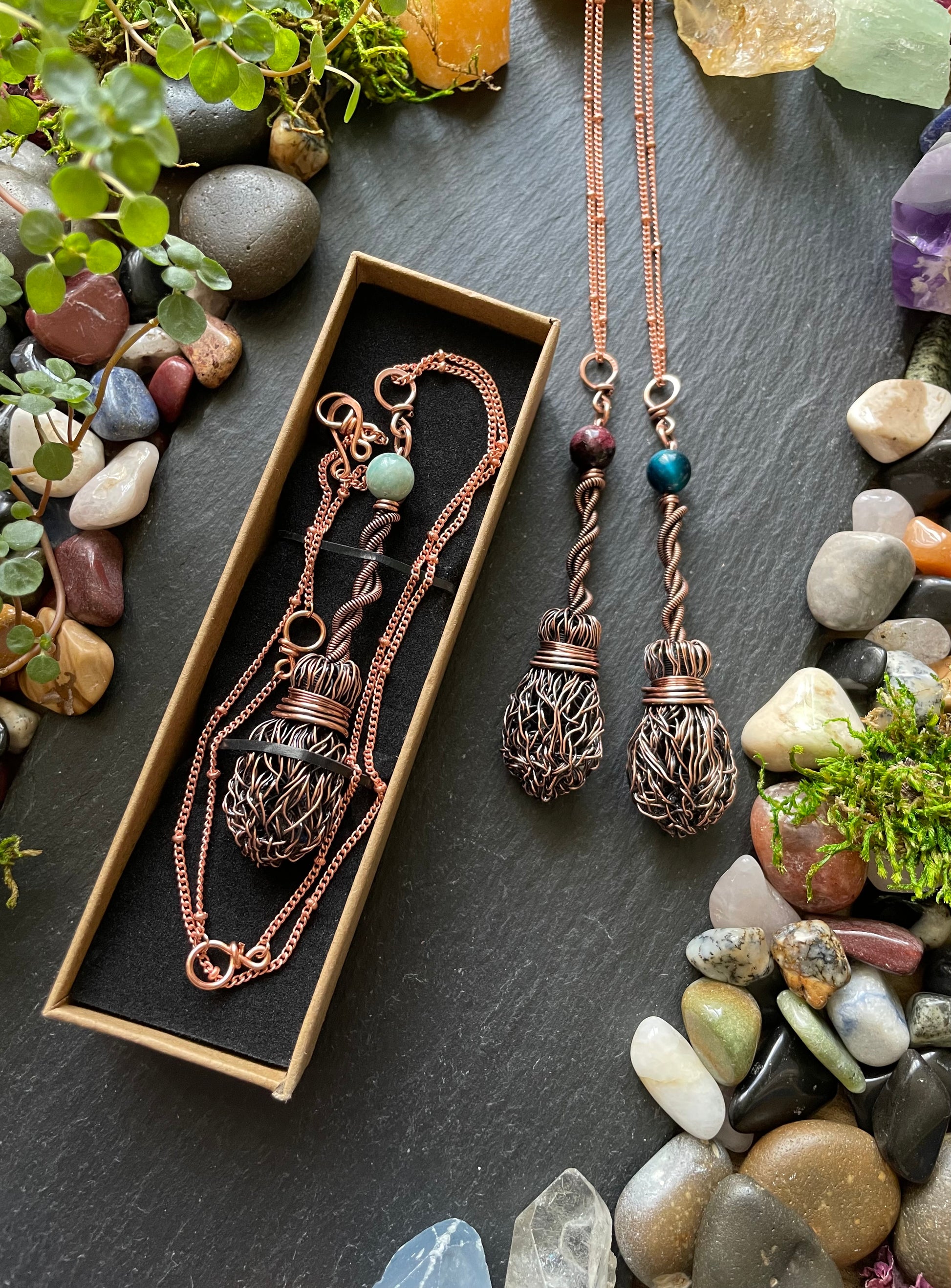 Copper necklaces with beads on a dark surface with stones and plants