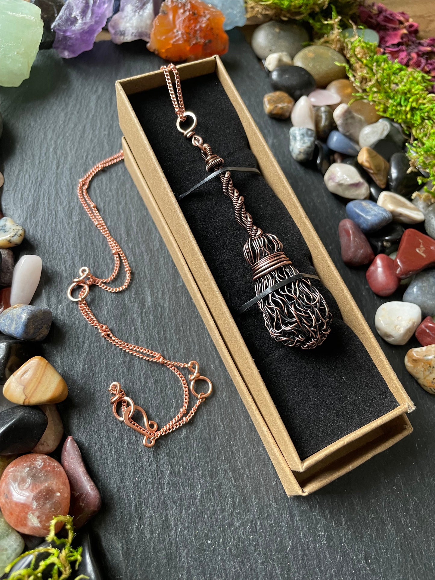 Copper necklace in a box with stones and crystals around