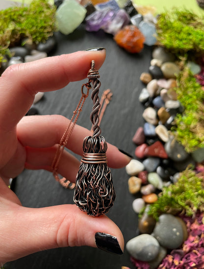 Hand holding a decorative pendant with a natural stone background